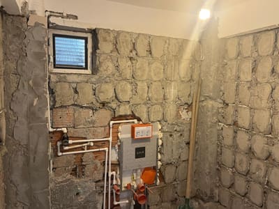 Rezervuar duvara gömüldü, su hatları duvarda dallandı. Pencere kanadı sökülmüş; yerinde yalnız kasa duruyor.