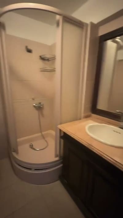 Köşe duşakabin, ahşap gövdeli lavabo dolabı, krem tezgâh.