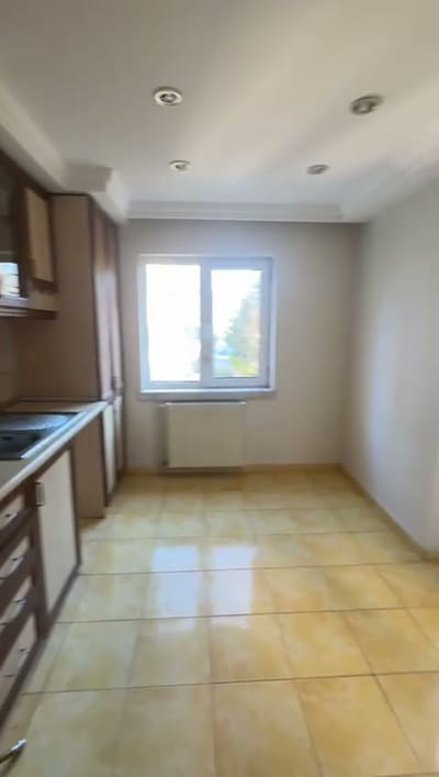 Kahverengi ahşap dolaplar, tezgâh altı çekmeceler, zeminde yine sarı seramik.
