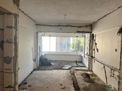 Balkon açıklığının üst bandı ve yanları tuğlaya kadar açık. Zeminde tesisat kanalları kazılmış, yeni gazbeton duvar sol tarafta örülmüş.