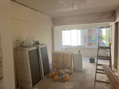 Alçı sıva ve perdah bitmiş; mekân artık tek hacim olarak okunuyor. Sağda büyük ebat seramik plakalar istiflenmiş.